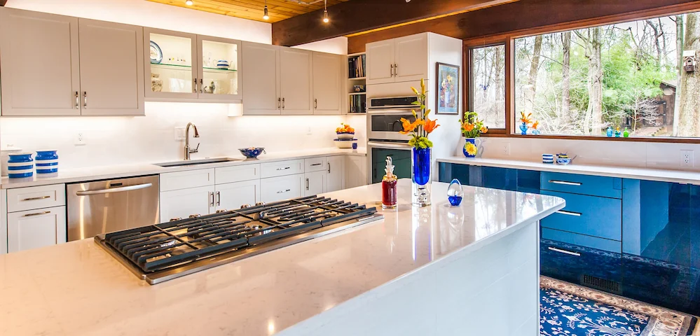 Modern kitchen remodel featuring white glossy subway tile backsplash, white quartz island, and natural wood cabinetry.