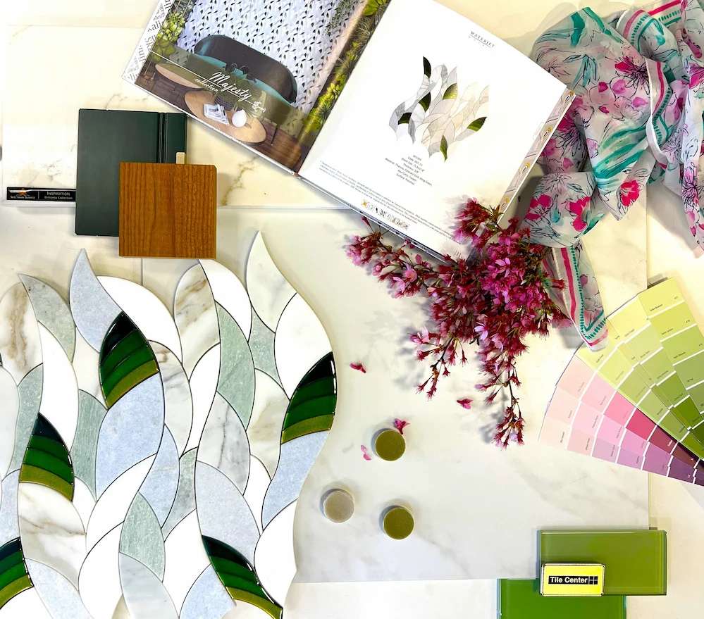 A design mood board featuring green glass tiles, leaf-shaped marble mosaic, wood samples, and pink paint swatches.