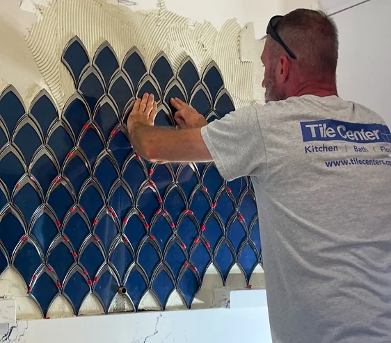 Modern kitchen featuring a blue scale mosaic backsplash, white marble countertops, and a professional stainless steel range.