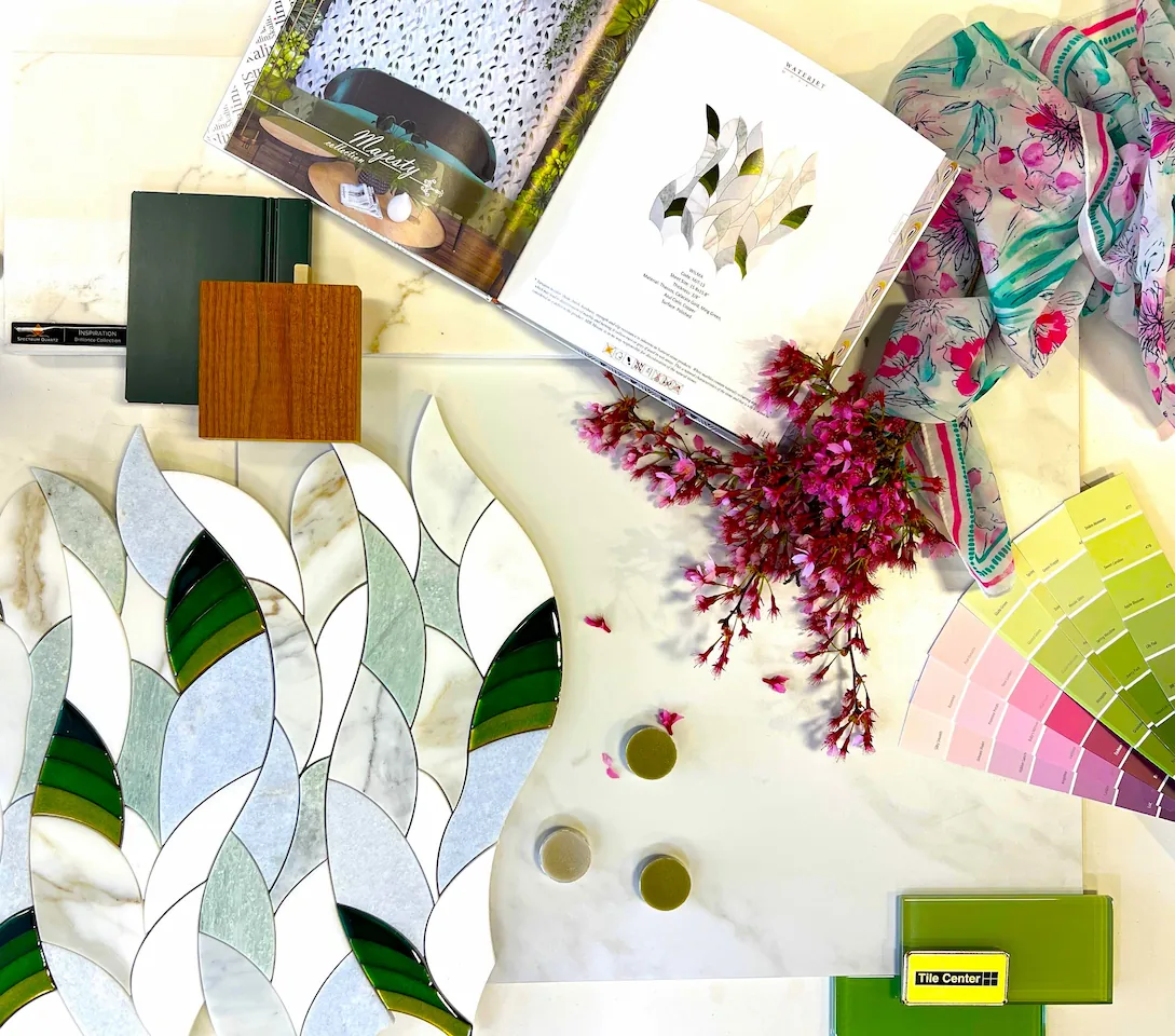 A design mood board featuring green glass tiles, leaf-shaped marble mosaic, wood samples, and pink paint swatches.